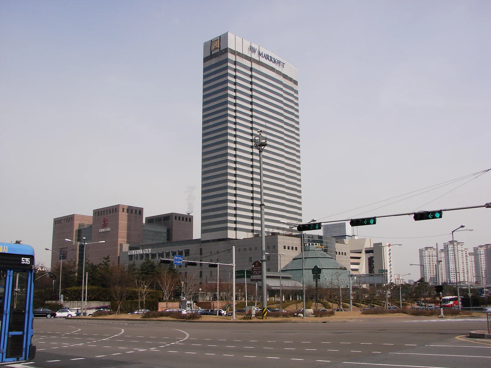 꼭대기에 JW MARRIOTT 간판이 달린 줄무늬 고층 건물과 그 앞의 넓은 교차로