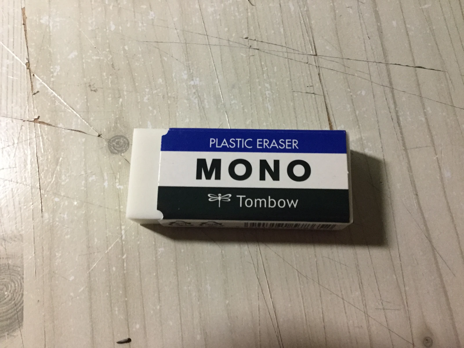 나무 책상 위 파랑·흰색·검정 케이스의 Tombow MONO 지우개